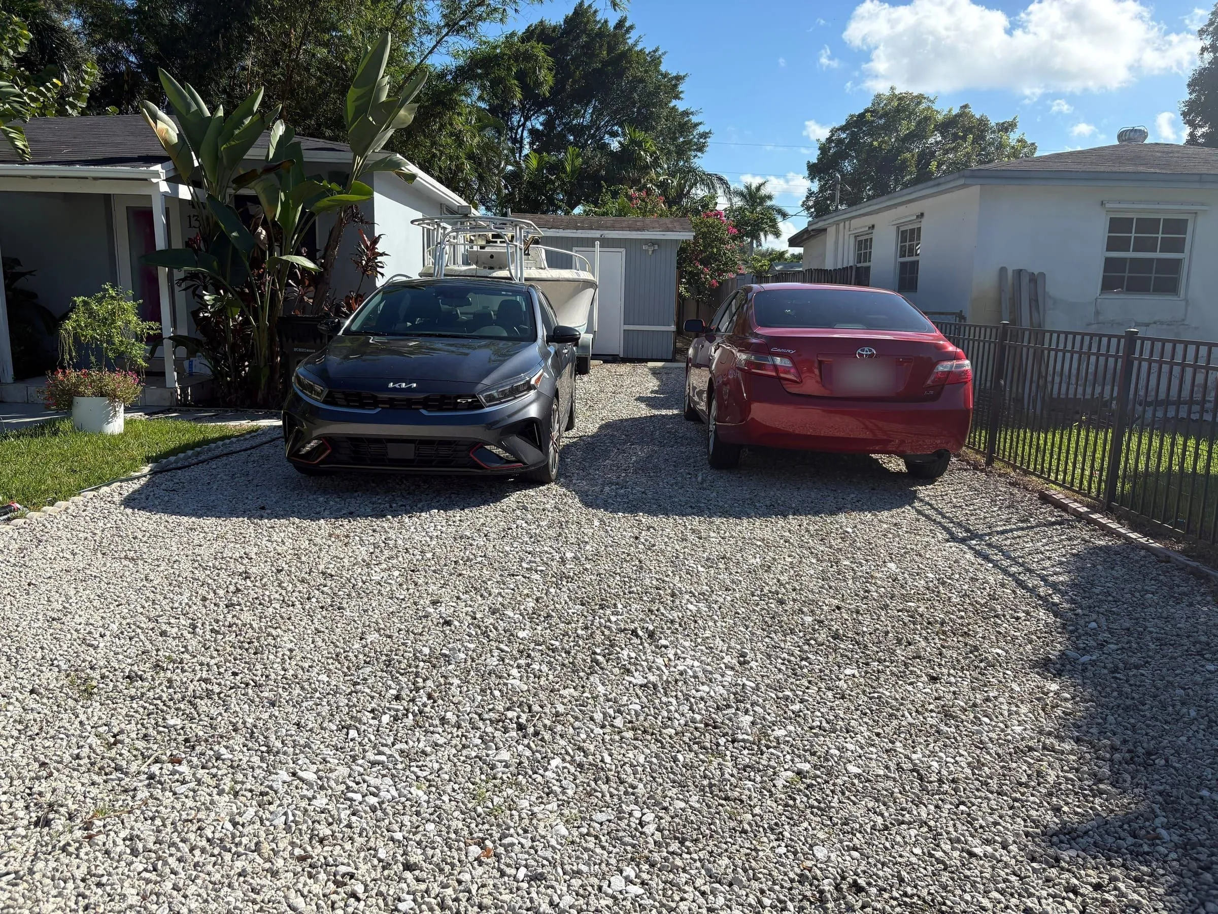 Loose gravel driveway with two parked cars in front of the house