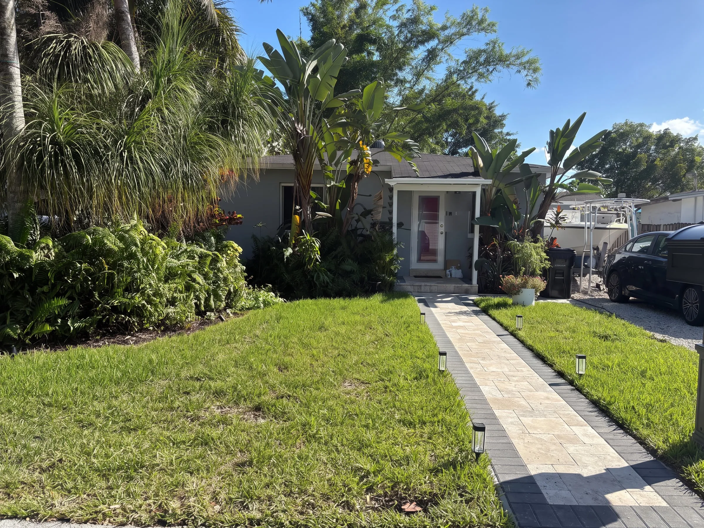 AI visualization of the same front yard with a wider travertine paver walkway and charcoal border
