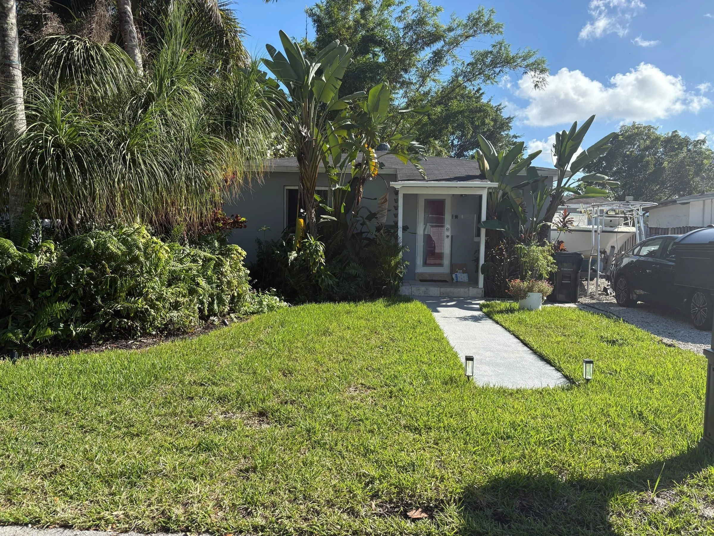 Front yard with a narrow plain concrete walkway to the entry