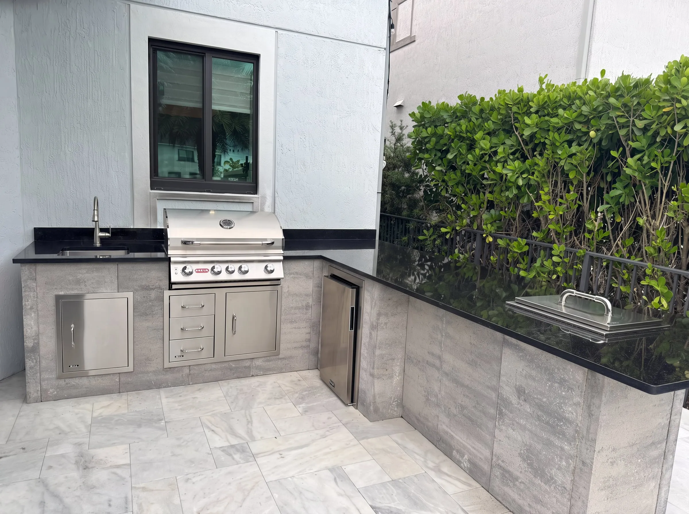 L-shaped outdoor kitchen with built-in grill, black granite counters and stone-look cabinets