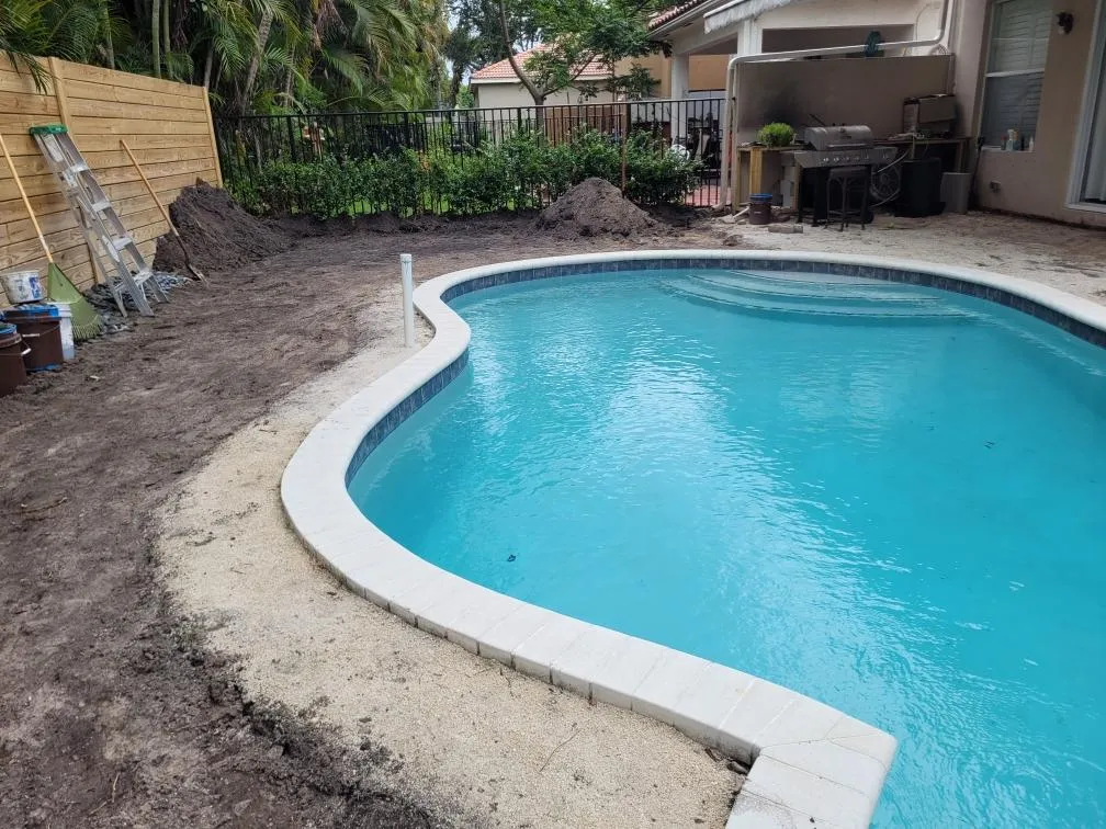 Backyard pool before the deck renovation, bare dirt and sand around the shell