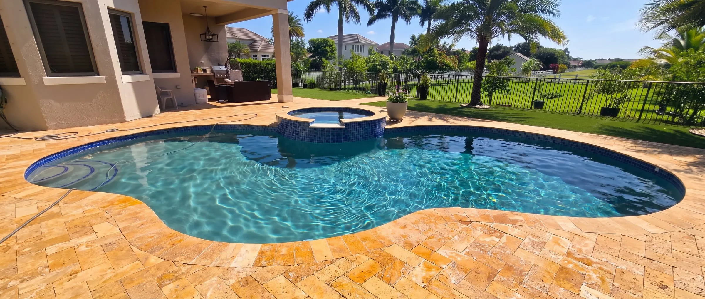 Pool with raised spa and travertine paver deck in a tropical yard