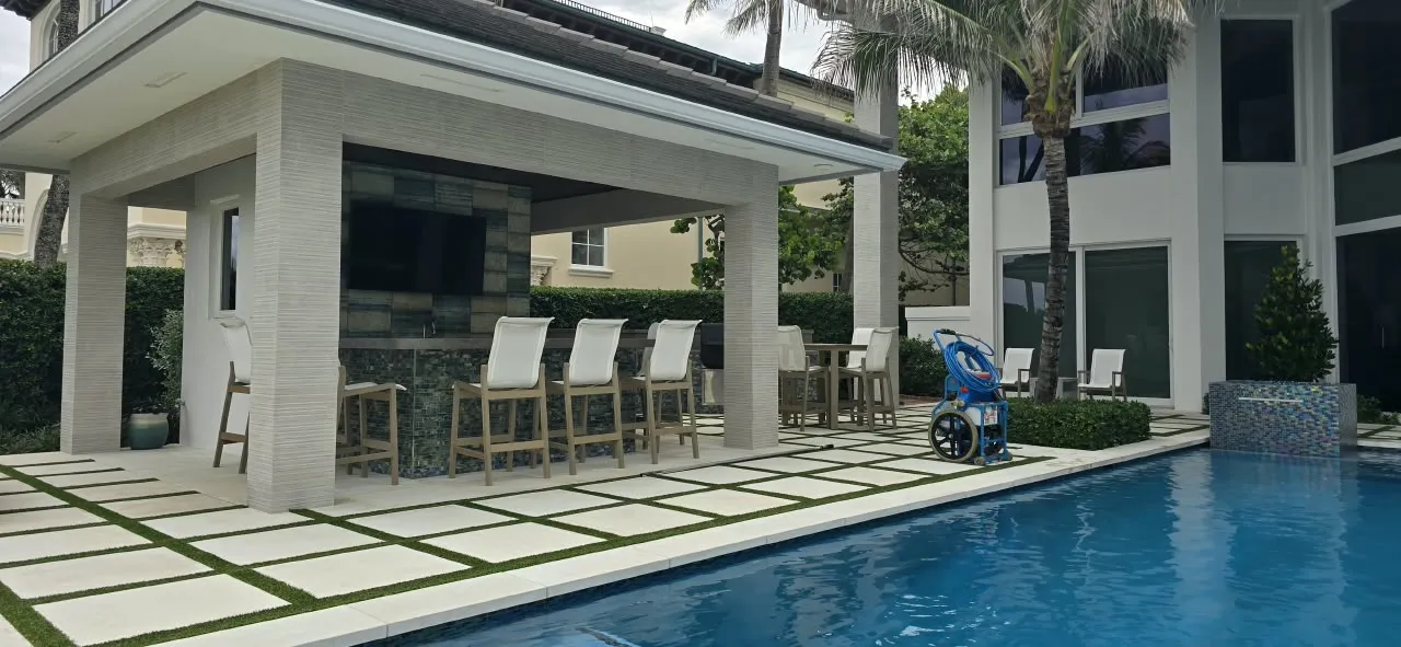 Covered poolside bar and lounge with paver and turf-inlay flooring