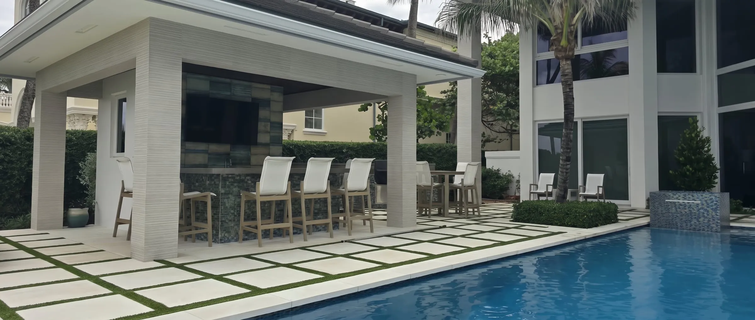 Covered outdoor bar and lounge with paver and turf-inlay flooring