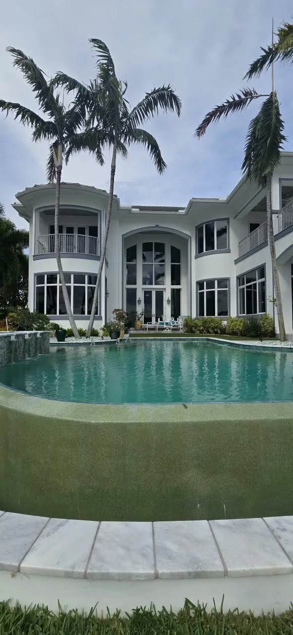 Resort-style pool patio with light travertine coping and palm landscaping