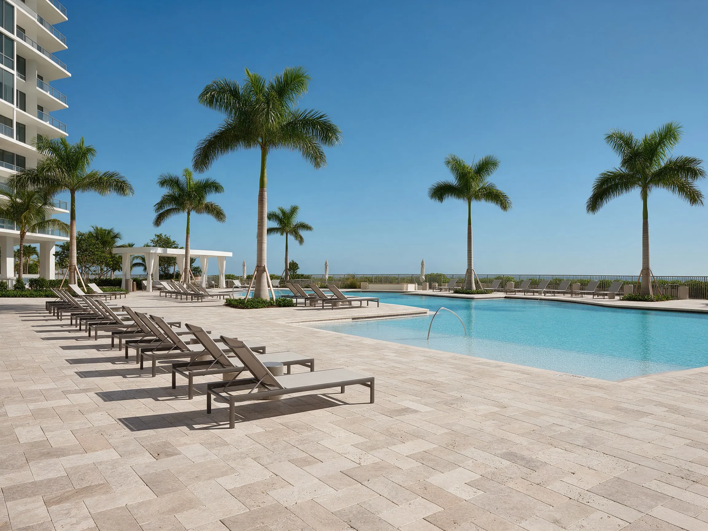 Resort-style condominium pool deck with light stone pavers